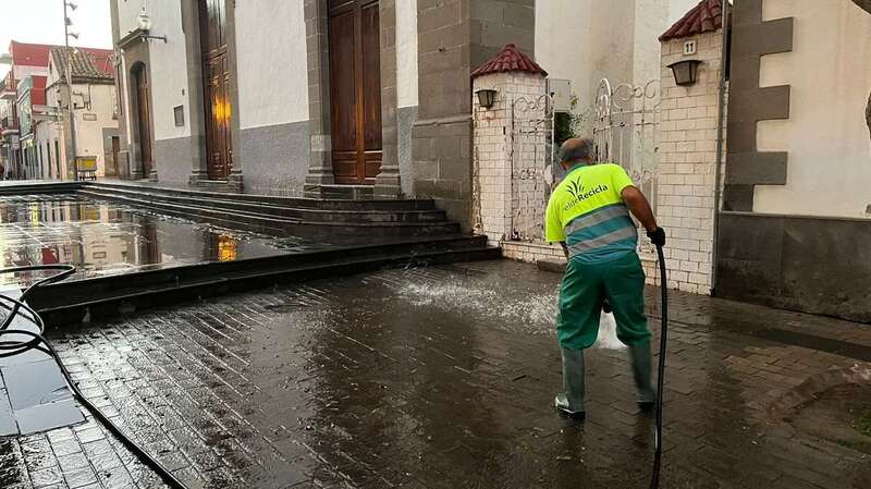 Operario limpiando con una manguera  el entorno de la plaza de Los Llanos/TA.